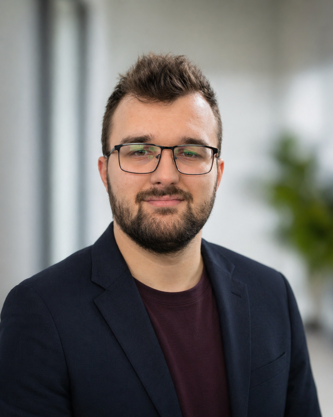 Porträt von Rudi Bott: Mann mit Brille, Vollbart und dunklem Sakko vor hellem, unscharfem Hintergrund